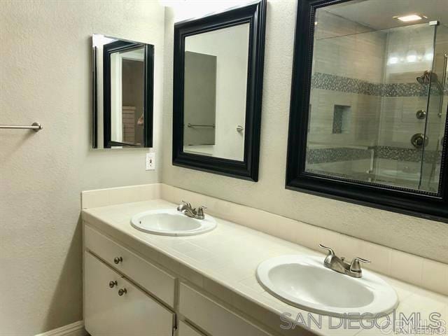 bathroom featuring a sink, a stall shower, double vanity, and a textured wall