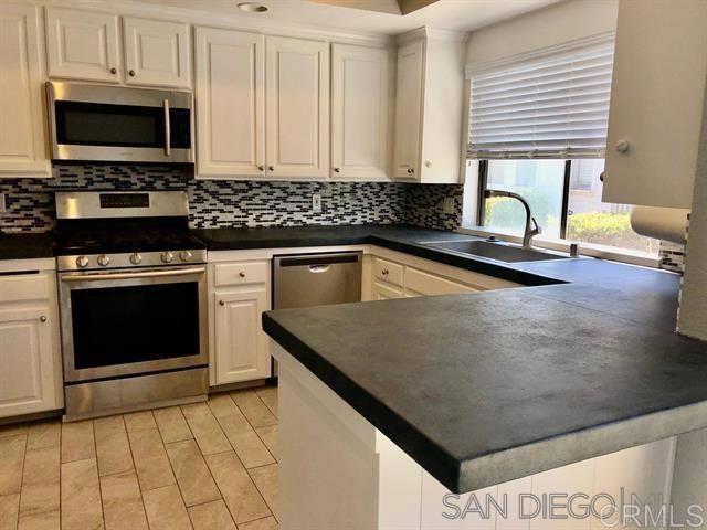 kitchen featuring a sink, dark countertops, appliances with stainless steel finishes, and white cabinetry