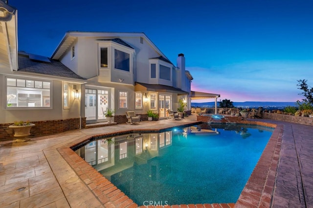 back of property featuring an outdoor pool, a chimney, a patio area, and stucco siding