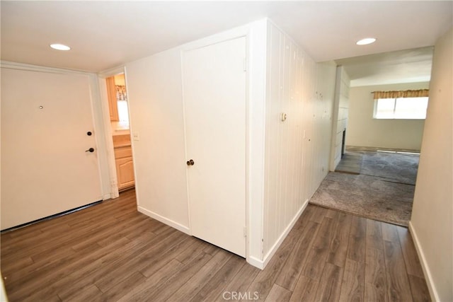 corridor with baseboards, wood finished floors, and recessed lighting