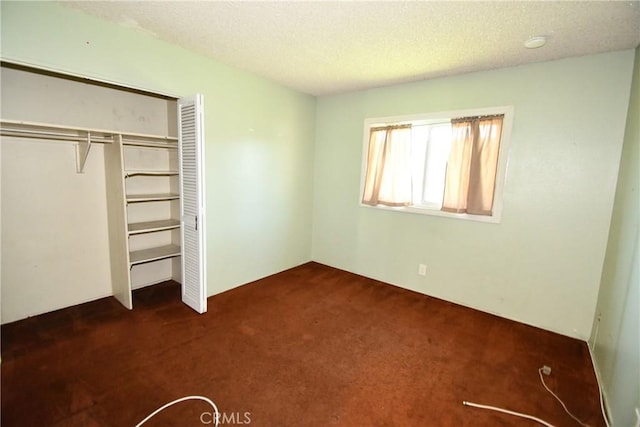 unfurnished bedroom featuring dark colored carpet, a closet, and a textured ceiling