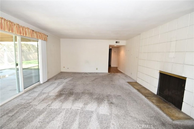 unfurnished living room with carpet and a tile fireplace