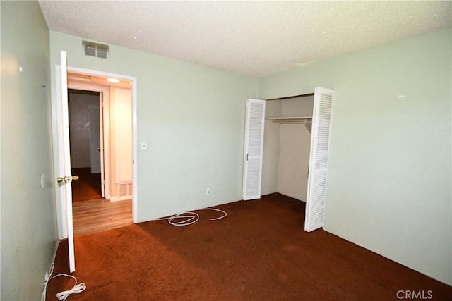 unfurnished bedroom with carpet floors, a closet, visible vents, and a textured ceiling