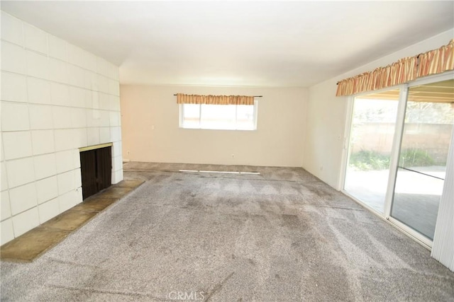 spare room featuring a fireplace and carpet flooring