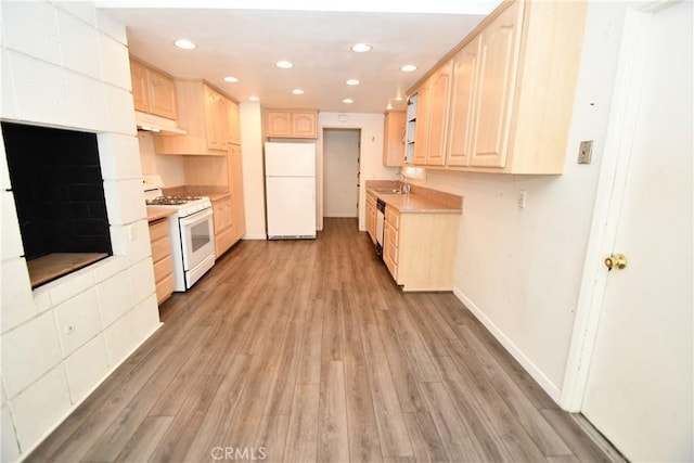 kitchen with white appliances, light brown cabinets, and light wood-style flooring