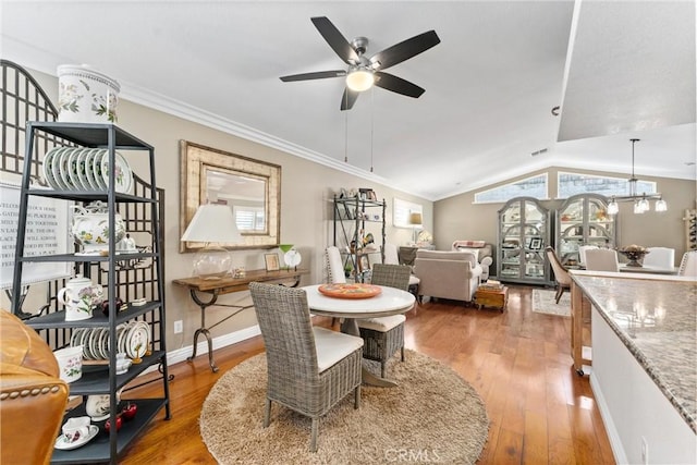 dining space with ornamental molding, vaulted ceiling, baseboards, and wood finished floors