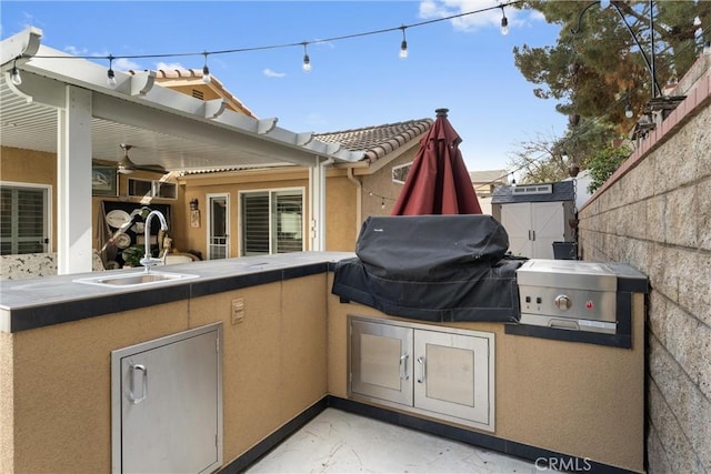 view of patio / terrace with exterior kitchen, fence, a sink, and area for grilling