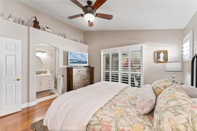 bedroom with lofted ceiling, wood finished floors, a ceiling fan, and ensuite bathroom