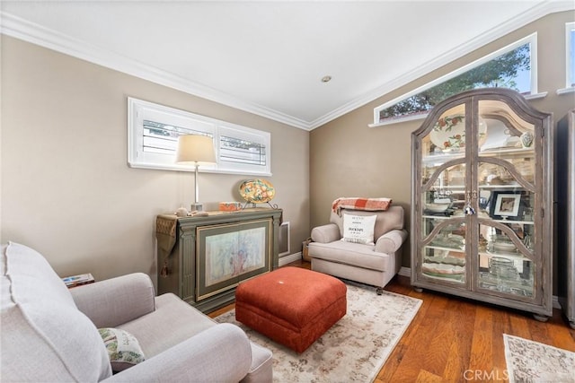 sitting room with ornamental molding and wood finished floors