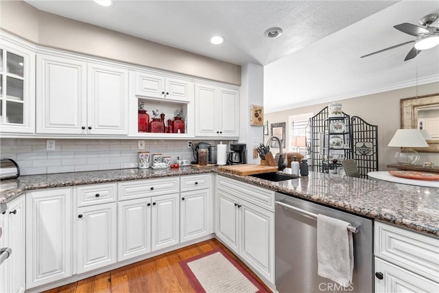 kitchen featuring light wood finished floors, white cabinets, decorative backsplash, stainless steel dishwasher, and a sink