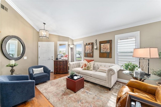 living area with baseboards, visible vents, wood finished floors, vaulted ceiling, and crown molding