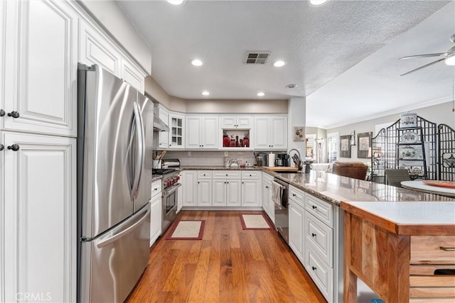 kitchen with visible vents, white cabinets, appliances with stainless steel finishes, a peninsula, and a sink