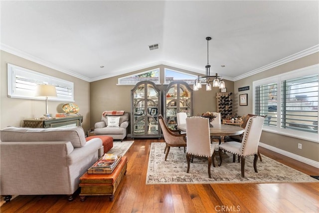 dining space featuring ornamental molding, lofted ceiling, visible vents, and hardwood / wood-style floors