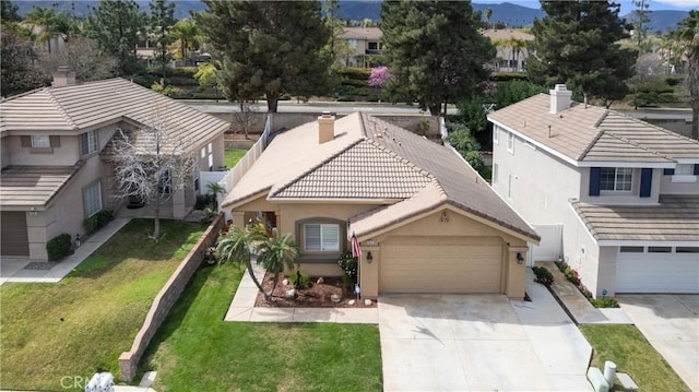 view of front of home with an attached garage, a front lawn, concrete driveway, and stucco siding