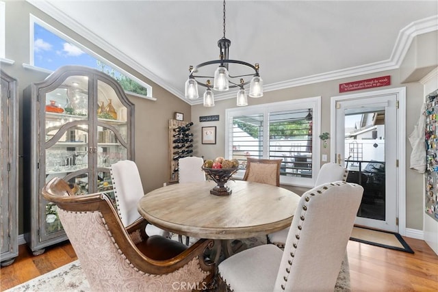 dining area with light wood-type flooring, baseboards, ornamental molding, and a chandelier