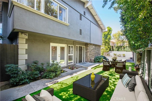 back of house with french doors, stucco siding, an outdoor hangout area, fence, and stone siding