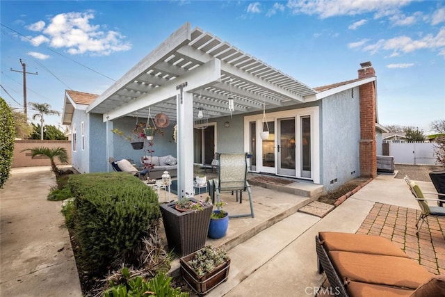 rear view of house featuring fence and stucco siding