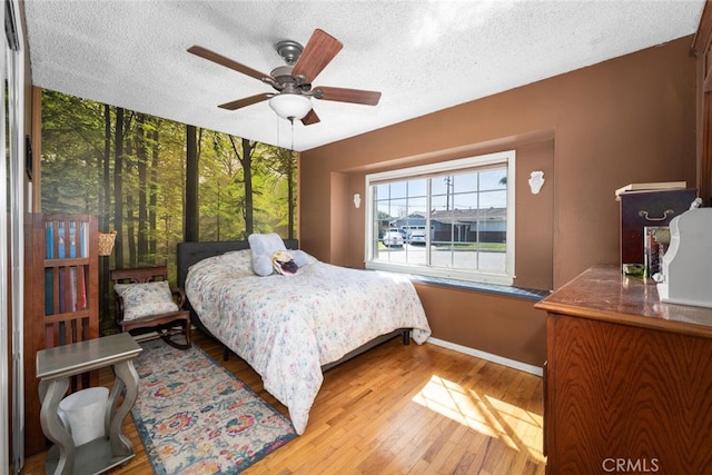 bedroom with ceiling fan, a textured ceiling, and hardwood / wood-style floors