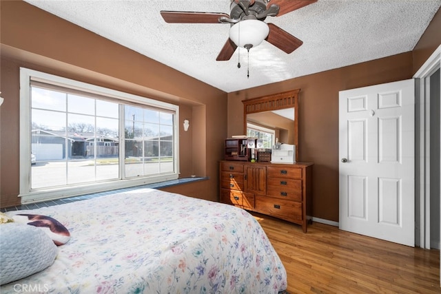 bedroom with a textured ceiling, wood finished floors, a ceiling fan, and baseboards