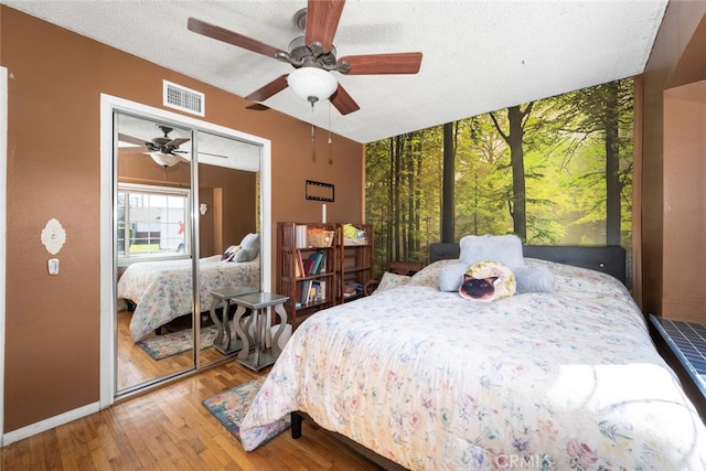 bedroom featuring visible vents, a ceiling fan, a textured ceiling, wood finished floors, and baseboards