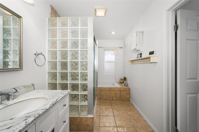 bathroom featuring tiled tub, baseboards, tiled shower, and vanity