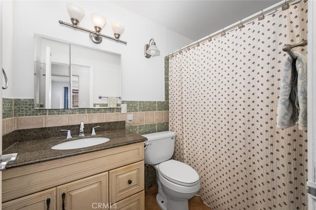 bathroom featuring toilet, curtained shower, tile walls, and vanity