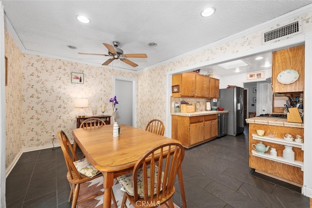 dining room featuring a textured ceiling, ornamental molding, visible vents, and wallpapered walls