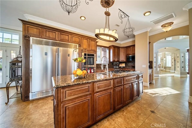 kitchen featuring arched walkways, plenty of natural light, appliances with stainless steel finishes, and a sink