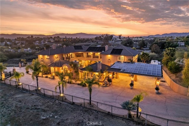 exterior space featuring a tile roof, fence, a mountain view, and roof mounted solar panels