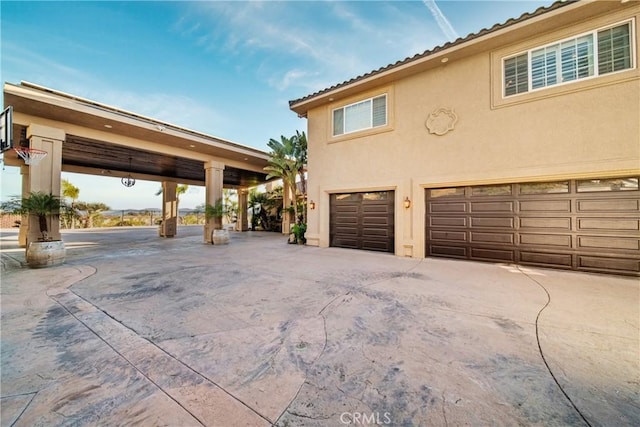 view of home's exterior featuring a tiled roof, a garage, and stucco siding