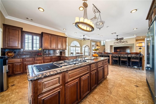 kitchen with visible vents, ornamental molding, a ceiling fan, a sink, and decorative backsplash