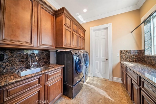 washroom with baseboards, cabinet space, a sink, crown molding, and washing machine and dryer