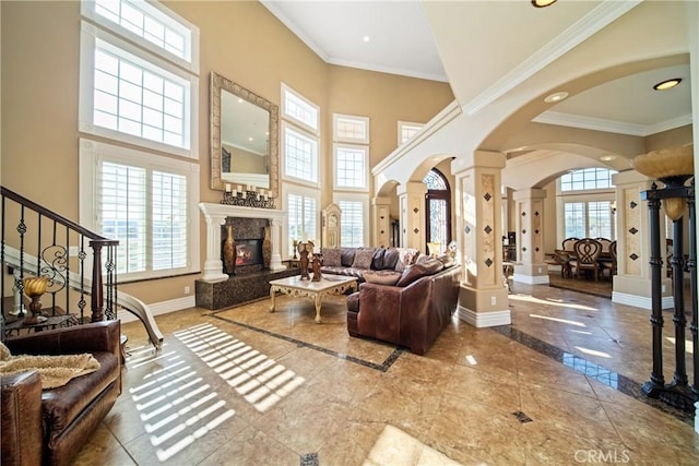 living area with ornate columns, baseboards, arched walkways, and a wealth of natural light