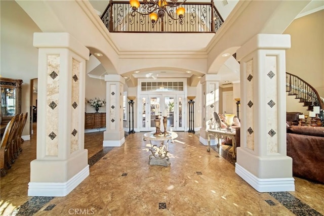 foyer with ornamental molding, stairway, arched walkways, a high ceiling, and baseboards