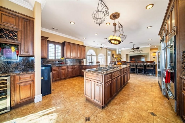 kitchen with a kitchen island with sink, beverage cooler, tasteful backsplash, open floor plan, and stainless steel stovetop