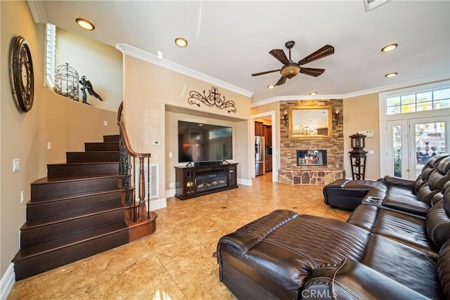 living room with crown molding, baseboards, stairway, a stone fireplace, and a ceiling fan