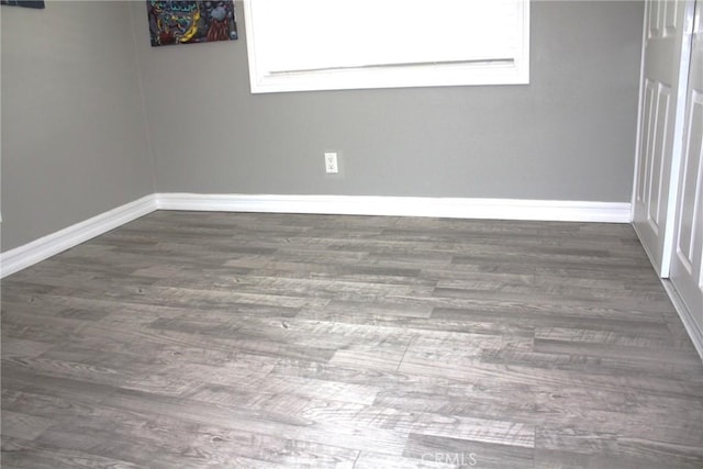 spare room featuring baseboards and wood finished floors