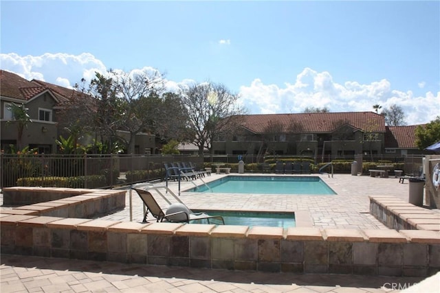 community pool featuring a patio, fence, and a hot tub