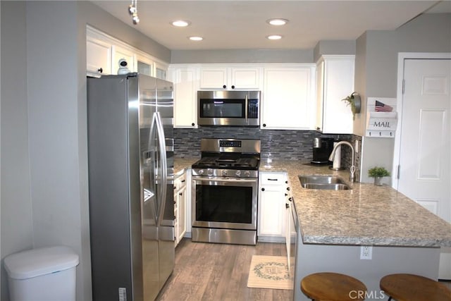 kitchen with light wood-style flooring, decorative backsplash, appliances with stainless steel finishes, white cabinets, and a sink