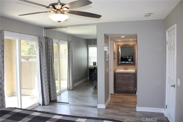 interior space with baseboards, connected bathroom, ceiling fan, wood finished floors, and a sink