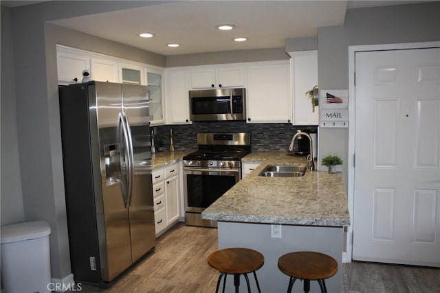 kitchen with decorative backsplash, stainless steel appliances, light wood-type flooring, white cabinetry, and a sink