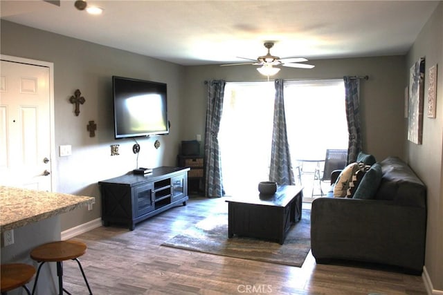 living room with ceiling fan, baseboards, and wood finished floors