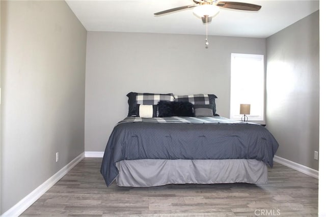 bedroom featuring a ceiling fan, baseboards, and wood finished floors