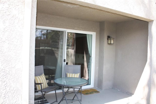 doorway to property with a patio area, outdoor dining space, and stucco siding