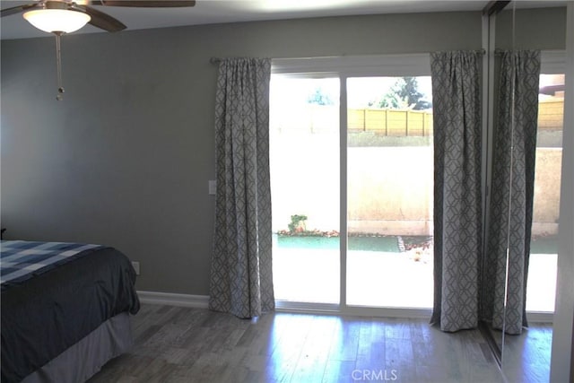 bedroom featuring access to exterior, a ceiling fan, baseboards, and wood finished floors