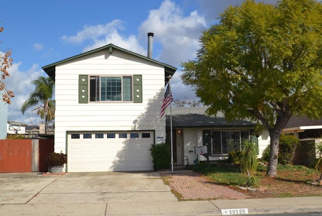 traditional-style house featuring concrete driveway, an attached garage, and fence