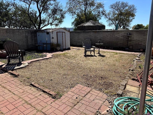 view of yard featuring an outbuilding, a fenced backyard, and a storage unit