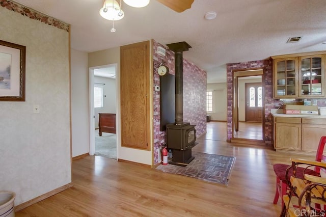interior space featuring light wood-style flooring, baseboards, glass insert cabinets, and visible vents