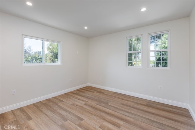 spare room featuring recessed lighting, light wood-type flooring, and baseboards