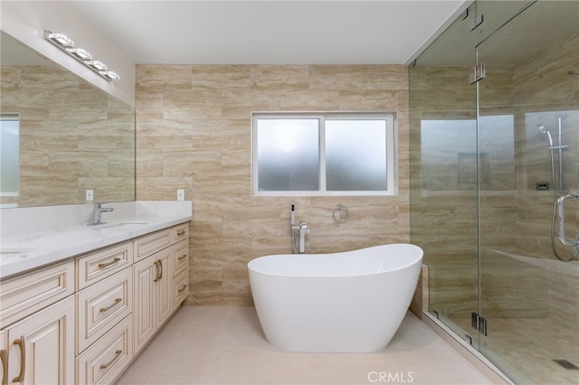 bathroom featuring a shower stall, double vanity, a freestanding tub, tile walls, and a sink